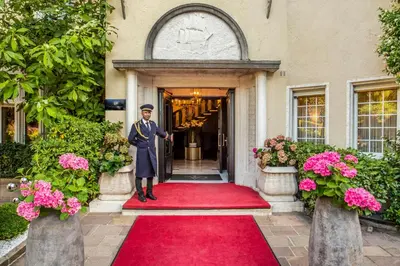 a man standing on a red carpet in front of a building at Villa Eden a member of Leading Hotels of the World in Merano