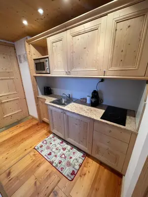 a kitchen with wooden cabinets and a sink and a wooden floor at Apartments Sol E Nef in Rocca Pietore