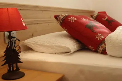 a bed with red and white pillows and a lamp at Apartments Sol E Nef in Rocca Pietore