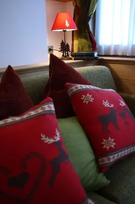 a couch with red pillows on it with a lamp at Apartments Sol E Nef in Rocca Pietore