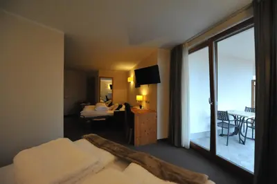a hotel room with a bed and a view of a balcony at Bio Hotel Brusago Vital & Wellness in Bedollo