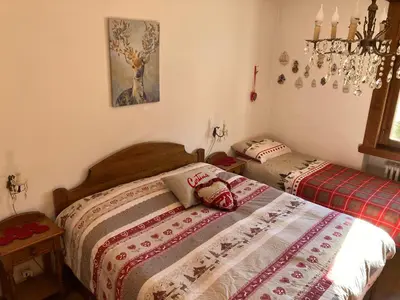 a bedroom with two beds and a chandelier at Affittacamere Iragidor in Cortina dʼAmpezzo