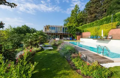 a garden with a swimming pool and a building at Hotel Goldener Stern in Caldaro