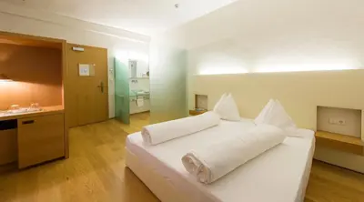 a bedroom with a white bed with white pillows at Hotel Goldener Stern in Caldaro
