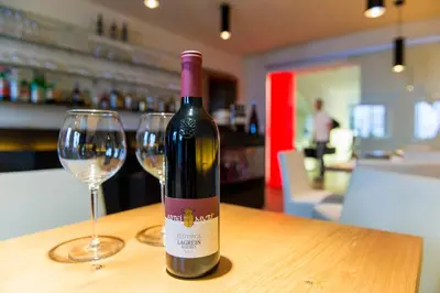 a bottle of wine sitting on a table with two glasses at Hotel Goldener Stern in Caldaro