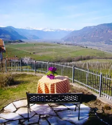 a person sitting on a bench looking out at a valley at Landhaus Weingut in Cornaiano