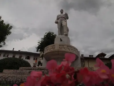 a statue in front of a building with pink flowers at Locanda Alpina in Brez