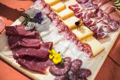 a plate of meats and cheese on a table at Hotel Costabella in Passo San Pellegrino