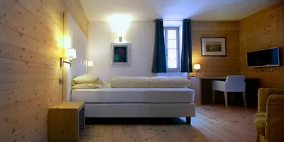 a bedroom with a bed and a table and a television at Hotel Costabella in Passo San Pellegrino