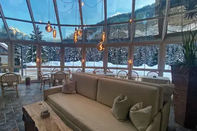 a living room with a couch in a room with windows at Turmchalet Adults Only in Braies
