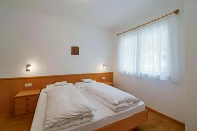 a bedroom with a bed with white sheets and a window at Ferienwohnungen Wieserhof in Andrian in Andrian