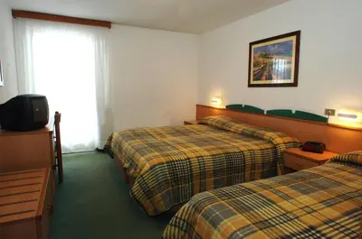 a hotel room with two beds and a television at Sport Hotel Pampeago in Tesero