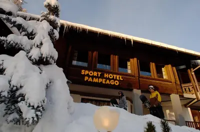 a snowboarder standing in front of a snow covered building at Sport Hotel Pampeago in Tesero