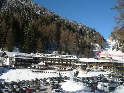 a large building with a lot of cars in the snow at Sport Hotel Pampeago in Tesero