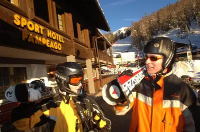 two people are standing in front of a ski lodge at Sport Hotel Pampeago in Tesero