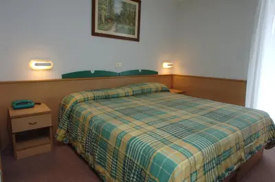 a hotel room with a bed with a plaid blanket at Sport Hotel Pampeago in Tesero