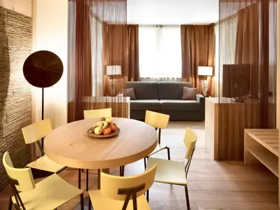 a living room with a table and yellow chairs at Color Home Suite Apartments in Predazzo