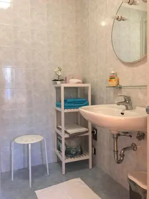 a bathroom with a sink and a mirror and a stool at Living Apartment Central in Merano