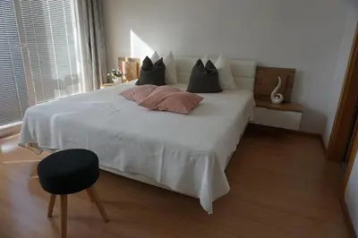 a bedroom with a white bed with pillows and a chair at Living Apartment Central in Merano