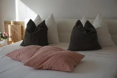 a bed with four pillows and a pink pillow on it at Living Apartment Central in Merano