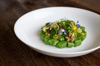 a white plate with a salad on a table at Kircherhof in Bressanone