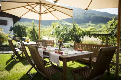 a wooden table with chairs and an umbrella at Kircherhof in Bressanone