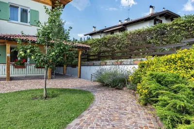 a garden with a brick walkway in front of a house at Affittacamere Villa Belfiore in Ronzone