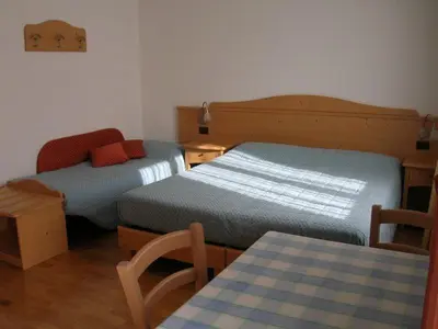 a bedroom with two beds and a table and a chair at Affittacamere Villa Belfiore in Ronzone