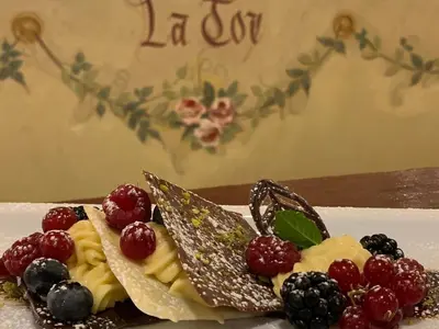 a plate with a dessert with fruit on it at Dolomit Boutique Hotel in La Villa