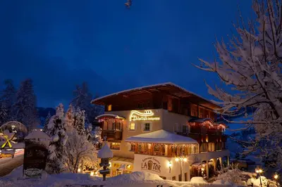 a building with christmas lights on it in the snow at Dolomit Boutique Hotel in La Villa