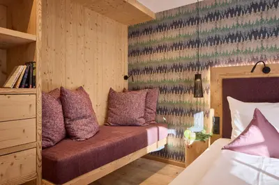 a bedroom with a bed with purple pillows at Dolomit Boutique Hotel in La Villa