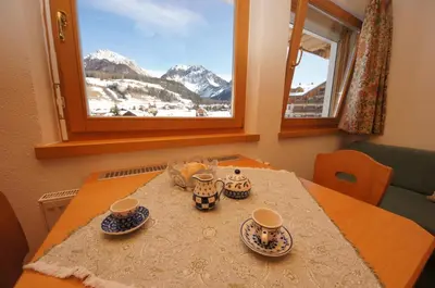 a table with cups and saucers on it with a window at Alfred Ties Apartments in San Vigilio Di Marebbe