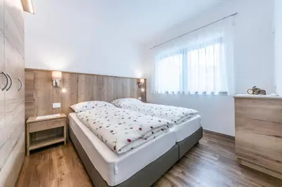 a bedroom with a bed with a wooden headboard at Alfred Ties Apartments in San Vigilio Di Marebbe
