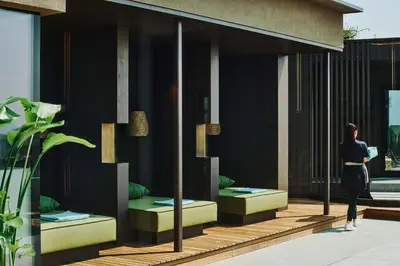 a woman walking past a building with benches at ALPIANA - green luxury Dolce Vita Hotel in Vollan