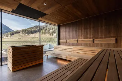 a large room with wooden benches and a large window at ALPIANA - green luxury Dolce Vita Hotel in Vollan