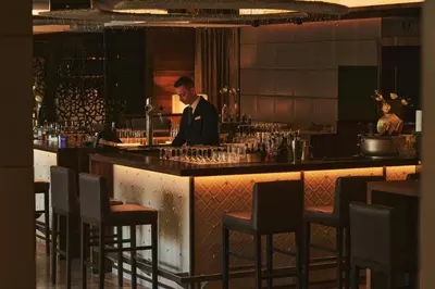 a man standing at a bar in a restaurant at ALPIANA - green luxury Dolce Vita Hotel in Vollan