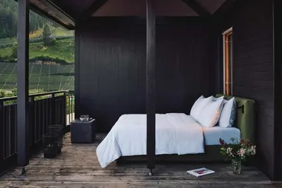 a bedroom with a bed on a porch with a window at ALPIANA - green luxury Dolce Vita Hotel in Vollan
