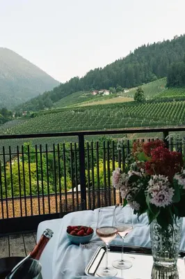 a table with a vase of flowers and wine glasses at ALPIANA - green luxury Dolce Vita Hotel in Vollan