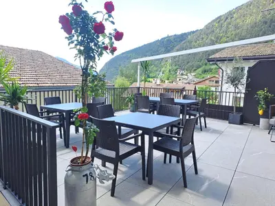 a patio with tables and chairs on a balcony at Zum Löwen-Post in Trodena