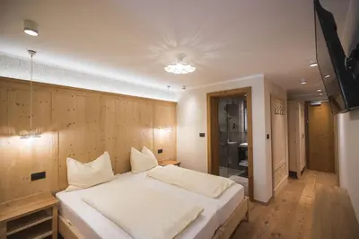 a bedroom with a large white bed in a room at Emma Historic Hotel in Villabassa