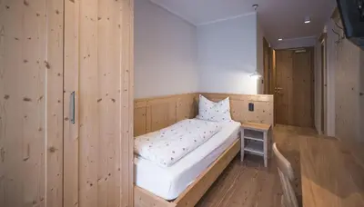a wooden room with a bed and a small table at Emma Historic Hotel in Villabassa