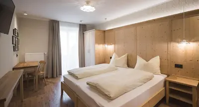 a bedroom with a large bed with a wooden wall at Emma Historic Hotel in Villabassa