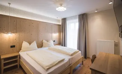 a bedroom with a large bed and a table at Emma Historic Hotel in Villabassa