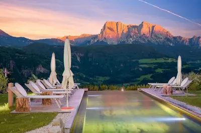 a group of chairs with umbrellas and a pool at Hotel-Chalet Pennhof in Barbiano