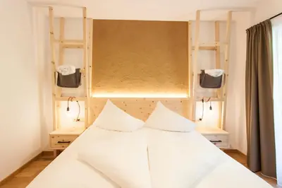 a bed with white sheets and pillows in a room at Hotel-Chalet Pennhof in Barbiano