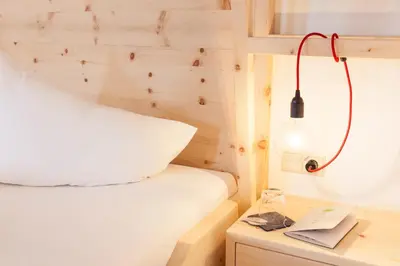 a bedroom with a bed and a desk with a lamp at Hotel-Chalet Pennhof in Barbiano
