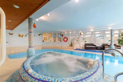 a swimming pool with a hot tub in the middle of a room at Pension Kofler in Vollan