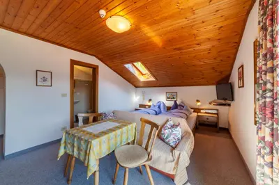 a bedroom with a bed and a table in a room at Pension Kofler in Vollan