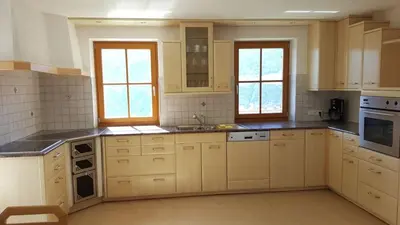 a large kitchen with white cabinets and windows at Rofenhof in Naturno