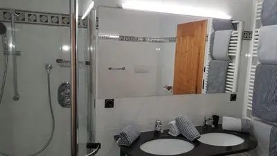 a bathroom with two sinks and a shower and a mirror at Rofenhof in Naturno